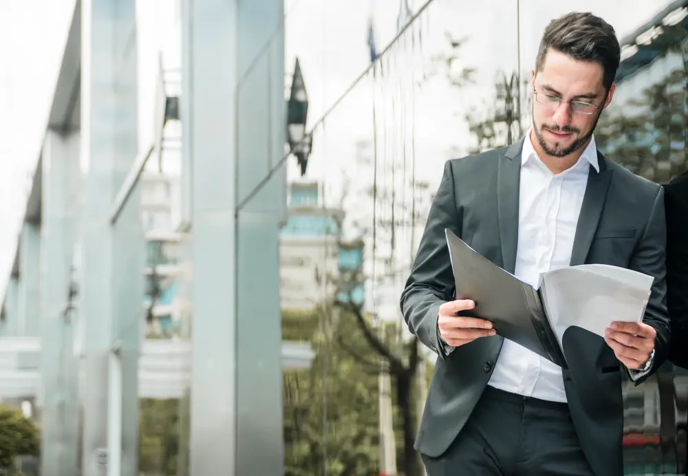 Hombre de negocios revisando documentos frente a un edificio corporativo, ilustrando una guía de declaración de impuestos corporativos en Estados Unidos