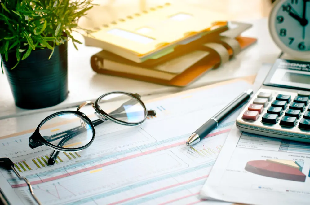 Documentos financieros, calculadora y gafas sobre escritorio usados para explicar qué son los taxes personales.