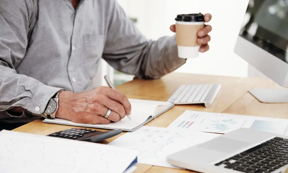 Ejecutivo revisando reportes financieros y tomando notas para declaracion de taxes corporativos