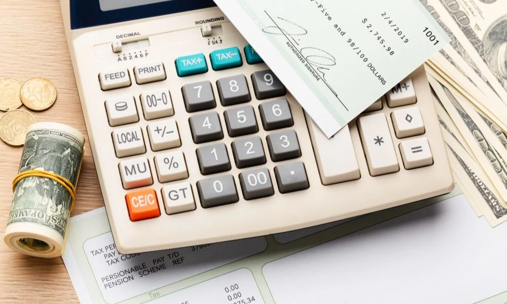 Calculadora, efectivo y formularios para declaración de taxes personales en USA sobre escritorio de oficina