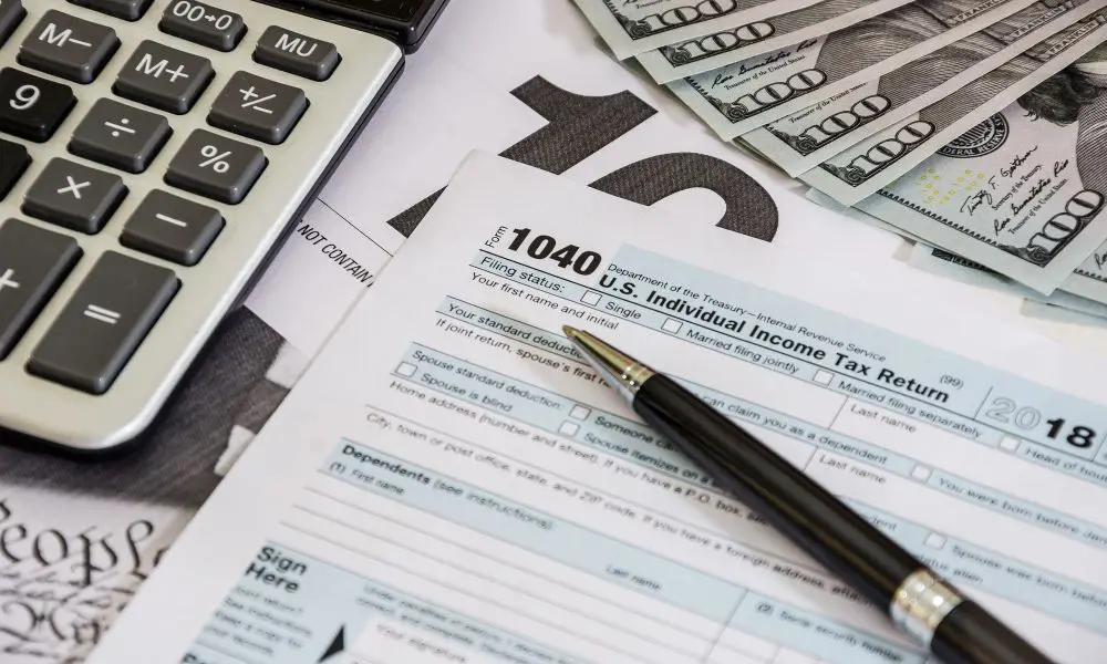 Formulario 1040 con calculadora, billetes y bolígrafo para declaración de taxes personales en USA