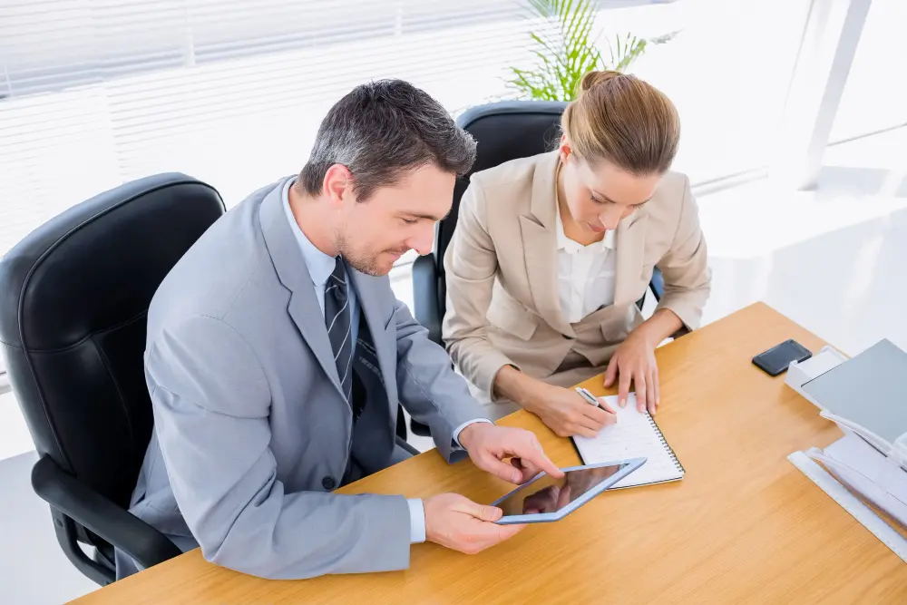 Asesores revisan tablet y toman notas sobre cómo optimizar taxes corporativos en una oficina